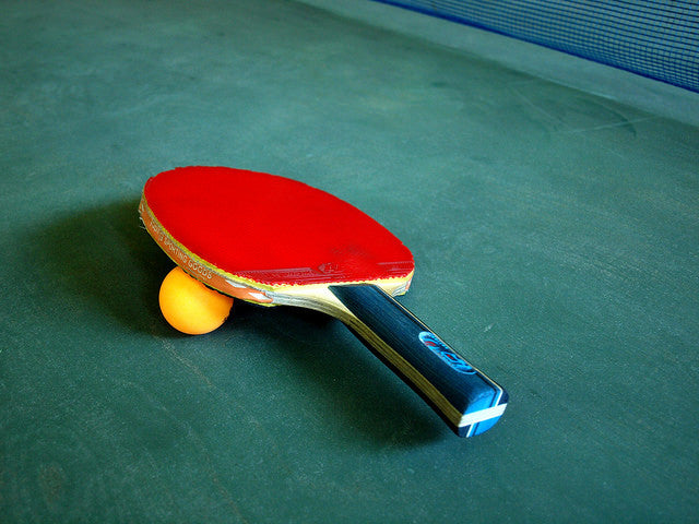 Ping pong paddle resting on ping pong ball